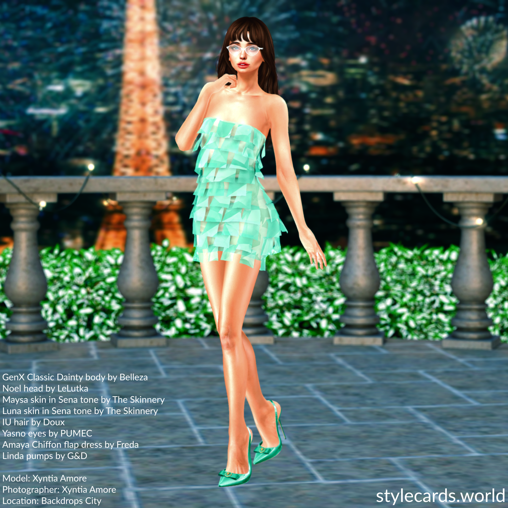 Xyntia Amore is standing on a patio in Paris at night as the Eiffel Tower shines brightly and firworks illuminate the sky. She is wearing a teal Amaya Chiffon Flap dress from Freda and a pair of matching teal Linda pumps from G&D.